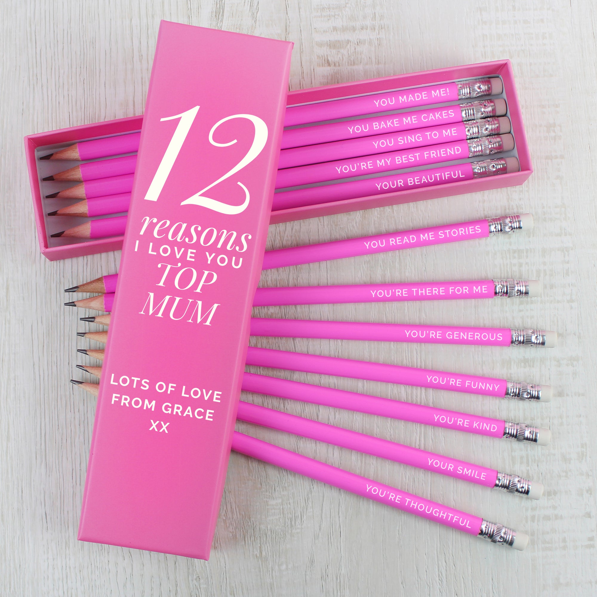 Box of 12 personalised pencils in a pink box. The box has fixed text printed in white which reads '12 reasons' which can be followed by a name and message of your choice which will also be printed in white below that. Inside the box are 12 HB writing pencils with a pink outer and an eraser on the top. Each pencil can be individually personalised with your own reasons why you love someone or other text of your choice.